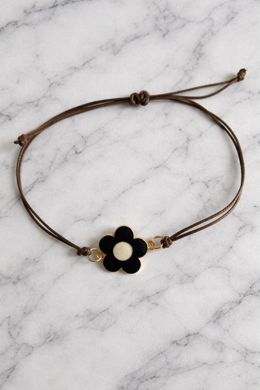 Bracelets noir et beige le cordon et de couleur marron la fleur est de couleur or en dessous 